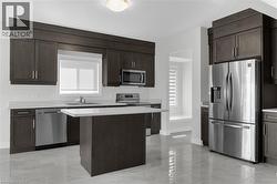 Kitchen featuring dark brown cabinetry, light countertops, stainless steel appliances, and a kitchen island - 