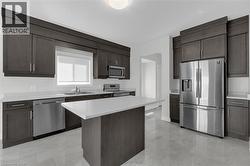 Kitchen with appliances with stainless steel finishes, light countertops, dark brown cabinets, and a kitchen island - 