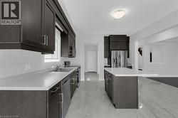 Kitchen with stainless steel appliances, light countertops, a center island, dark brown cabinets, and a kitchen bar - 