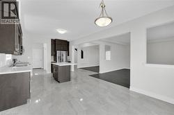 Kitchen featuring dark brown cabinetry, light countertops, hanging light fixtures, a center island, and stainless steel appliances - 