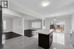 Kitchen featuring a kitchen island, open floor plan, light countertops, pendant lighting, and plenty of natural light - 