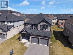 View of front facade featuring a residential view, roof with shingles, a front yard, and asphalt driveway - 