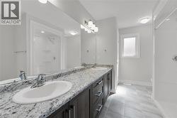 Full bath featuring a walk in shower, double vanity, and light tile patterned floors - 
