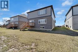 Rear view of property featuring brick siding, stairs, a lawn, and a deck - 