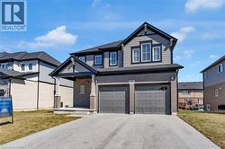 View of front facade with a front yard, driveway, an attached garage, and brick siding - 
