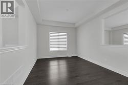Empty room with dark wood-style floors and a tray ceiling - 