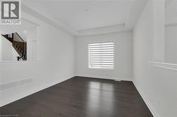 Unfurnished room featuring stairs and dark wood finished floors - 