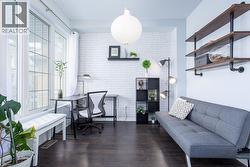 Office with brick wall, wood finished floors, visible vents, and plenty of natural light - 