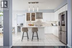 Kitchen featuring light countertops, stainless steel fridge, wall chimney exhaust hood, and decorative backsplash - 
