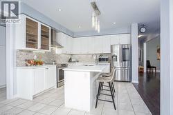 Kitchen featuring wall chimney range hood, tasteful backsplash, a sink, stainless steel appliances, and light countertops - 