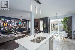 Kitchen featuring stainless steel dishwasher, a sink, hanging light fixtures, open floor plan, and light countertops - 