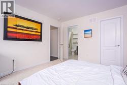 Carpeted bedroom featuring baseboards, ensuite bath, and visible vents - 