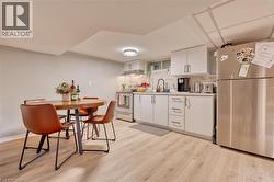 Kitchen featuring white cabinets, backsplash, light hardwood / wood-style floors, and stainless steel appliances - 