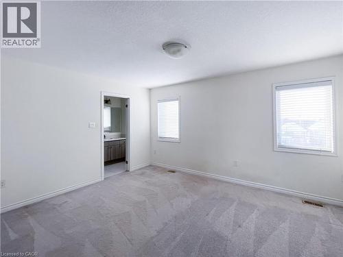 Unfurnished bedroom with light colored carpet, a textured ceiling, and connected bathroom - 116 Watermill Street, Kitchener, ON - Indoor Photo Showing Other Room