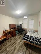 Bedroom with a desk, a textured ceiling, and dark wood finished floors - 