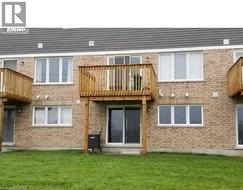 Back of property with a balcony, brick siding, and a lawn - 