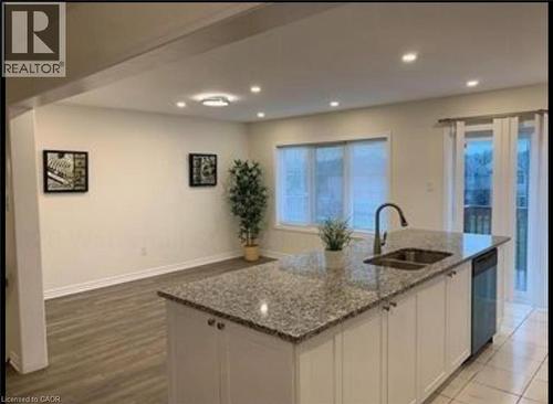 Kitchen featuring white cabinetry, light stone counters, a kitchen island with sink, recessed lighting, and stainless steel dishwasher - 128 Watermill Street, Kitchener, ON - Indoor Photo Showing Kitchen With Double Sink