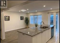 Kitchen featuring white cabinetry, light stone counters, a kitchen island with sink, recessed lighting, and stainless steel dishwasher - 