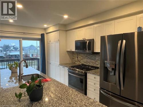 Kitchen with appliances with stainless steel finishes, white cabinets, decorative backsplash, recessed lighting, and light stone counters - 128 Watermill Street, Kitchener, ON - Indoor Photo Showing Kitchen