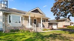 View of front of property with stone siding, covered porch, a front yard, asphalt driveway, and roof with shingles - 