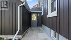 Doorway to property featuring board and batten siding and a shingled roof - 
