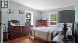 Bedroom with dark wood-style flooring, multiple windows, and ornamental molding - 
