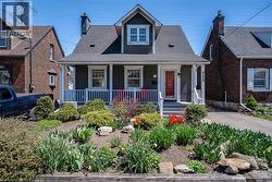 View of front of house featuring roof with shingles, covered porch, and a chimney - 