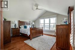 Bedroom featuring lofted ceiling, wood finished floors, and a ceiling fan - 