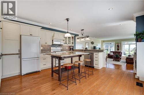 Kitchen featuring white appliances, glass insert cabinets, open floor plan, decorative light fixtures, and white cabinets - 849 Beach Boulevard, Hamilton, ON - Indoor Photo Showing Kitchen