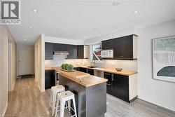 Kitchen with a kitchen island, a breakfast bar area, decorative backsplash, under cabinet range hood, and white microwave - 