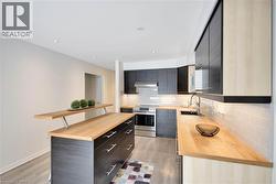 Kitchen featuring stainless steel range with electric cooktop, light wood-type flooring, wood counters, tasteful backsplash, and a center island - 