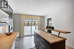 Kitchen featuring butcher block counters, white microwave, light wood finished floors, modern cabinets, and recessed lighting - 