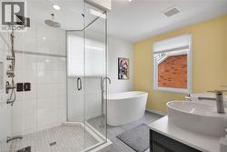 Full bathroom featuring double vanity, a stall shower, and a freestanding bath - 