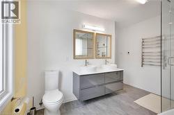 Full bathroom with radiator, double vanity, a stall shower, and a towel warming rack - 