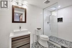 Full bath featuring tile walls, walk in shower, vanity, and tile patterned flooring - 
