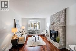 Living room with dark wood finished floors, a textured ceiling, and a brick fireplace - 