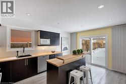 Kitchen with a kitchen breakfast bar, decorative backsplash, dishwasher, white microwave, and butcher block countertops - 