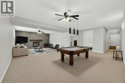 Rec room featuring a ceiling fan, a large fireplace, pool table, light colored carpet, and recessed lighting - 