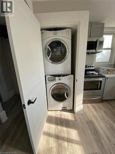 Washroom with light wood finished floors and stacked washing machine and dryer - 193 Balmoral Avenue N, Hamilton, ON - Indoor Photo Showing Laundry Room