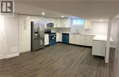 Kitchen with stainless steel fridge, electric range, white cabinetry, dark wood-style flooring, and recessed lighting - 557 Lake Street, St. Catharines, ON - Indoor Photo Showing Kitchen With Double Sink