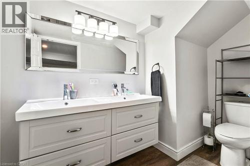 Bathroom featuring double vanity, dark wood-style floors, and vaulted ceiling - 557 Lake Street, St. Catharines, ON - Indoor Photo Showing Bathroom