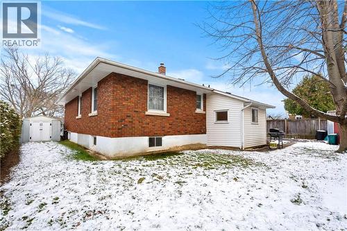 Snow covered property featuring a chimney, brick siding, and a storage shed - 557 Lake Street, St. Catharines, ON - Outdoor With Exterior