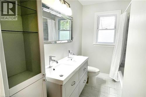 Bathroom featuring double vanity, light marble finish flooring, and shower / bath combo with shower curtain - 557 Lake Street, St. Catharines, ON - Indoor Photo Showing Bathroom