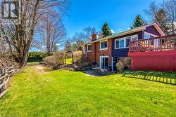 Rear view of house with a chimney, fence, a wooden deck, brick siding, and a yard - 