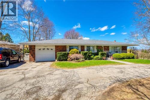 Ranch-style home featuring a garage, brick siding, a front yard, and aphalt driveway - 1215 Britannia Road, Burlington, ON 