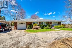 Ranch-style home featuring a garage, brick siding, a front yard, and aphalt driveway - 