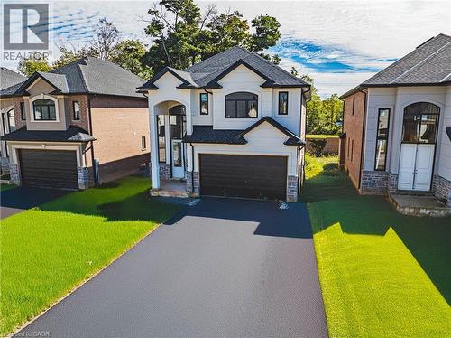 French country inspired facade with a front lawn, a garage, stone siding, and asphalt driveway - 56 Cesar Place, Ancaster, ON - Outdoor With Facade