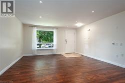 Empty room with dark wood-style floors and recessed lighting - 