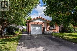 View of front of property featuring asphalt driveway, brick siding, a front lawn, and an attached garage - 