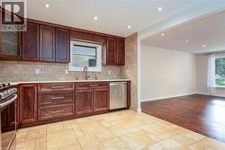 Kitchen with recessed lighting, light stone countertops, appliances with stainless steel finishes, tasteful backsplash, and dark brown cabinetry - 